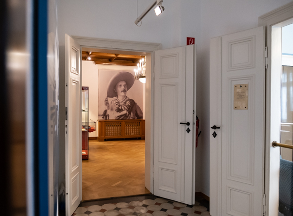 Blick durch die geöffneten Türen ins einstige Esszimmer. An der Wand hängt das Foto von Alois Schießer, der Karl May als Old Shatterhand porträtiert. 